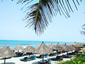 beach view with summer umbrellas, palm leaf, turquoise water, white beach